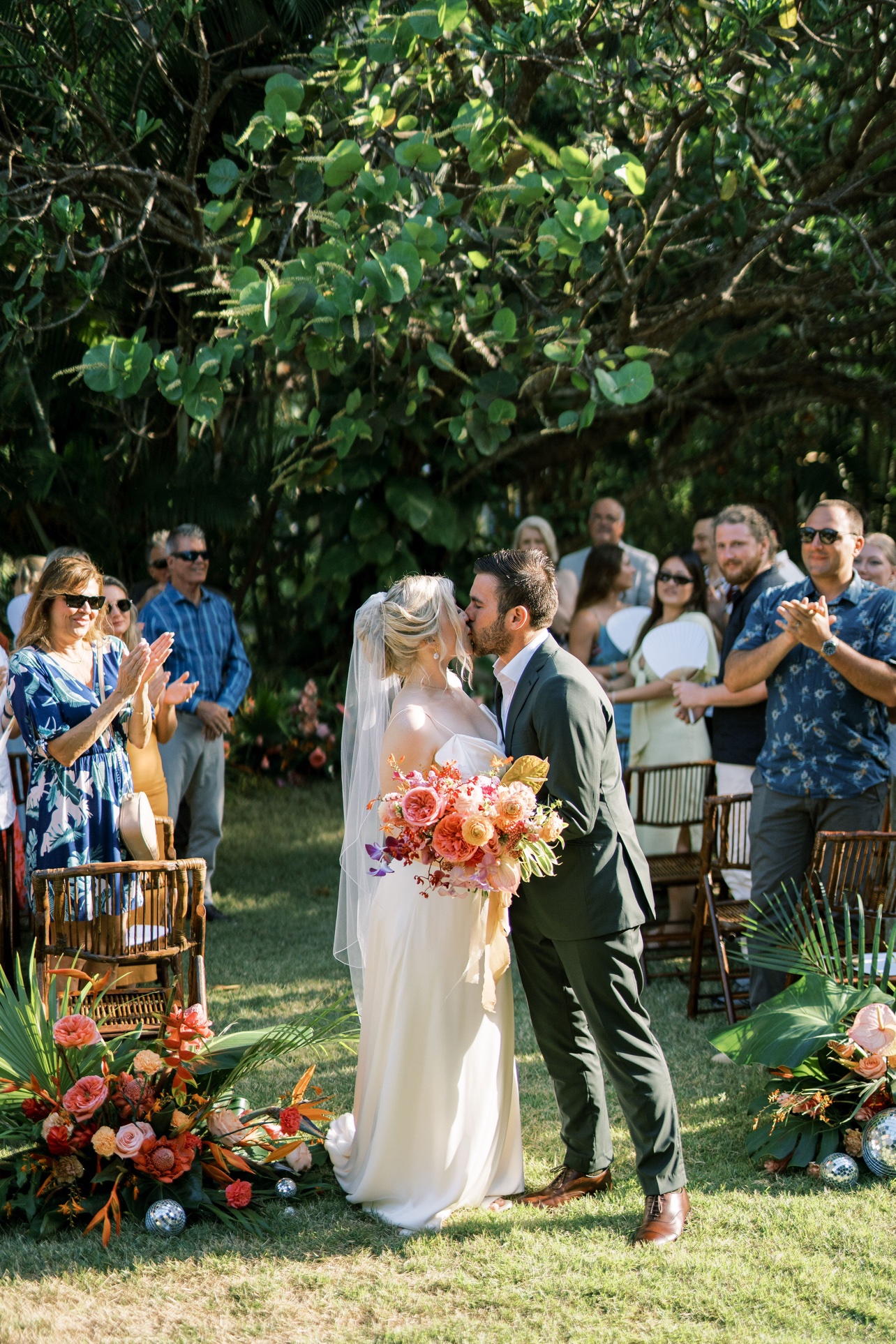 Beso de los novios durante la ceremonia con invitados aplaudiendo