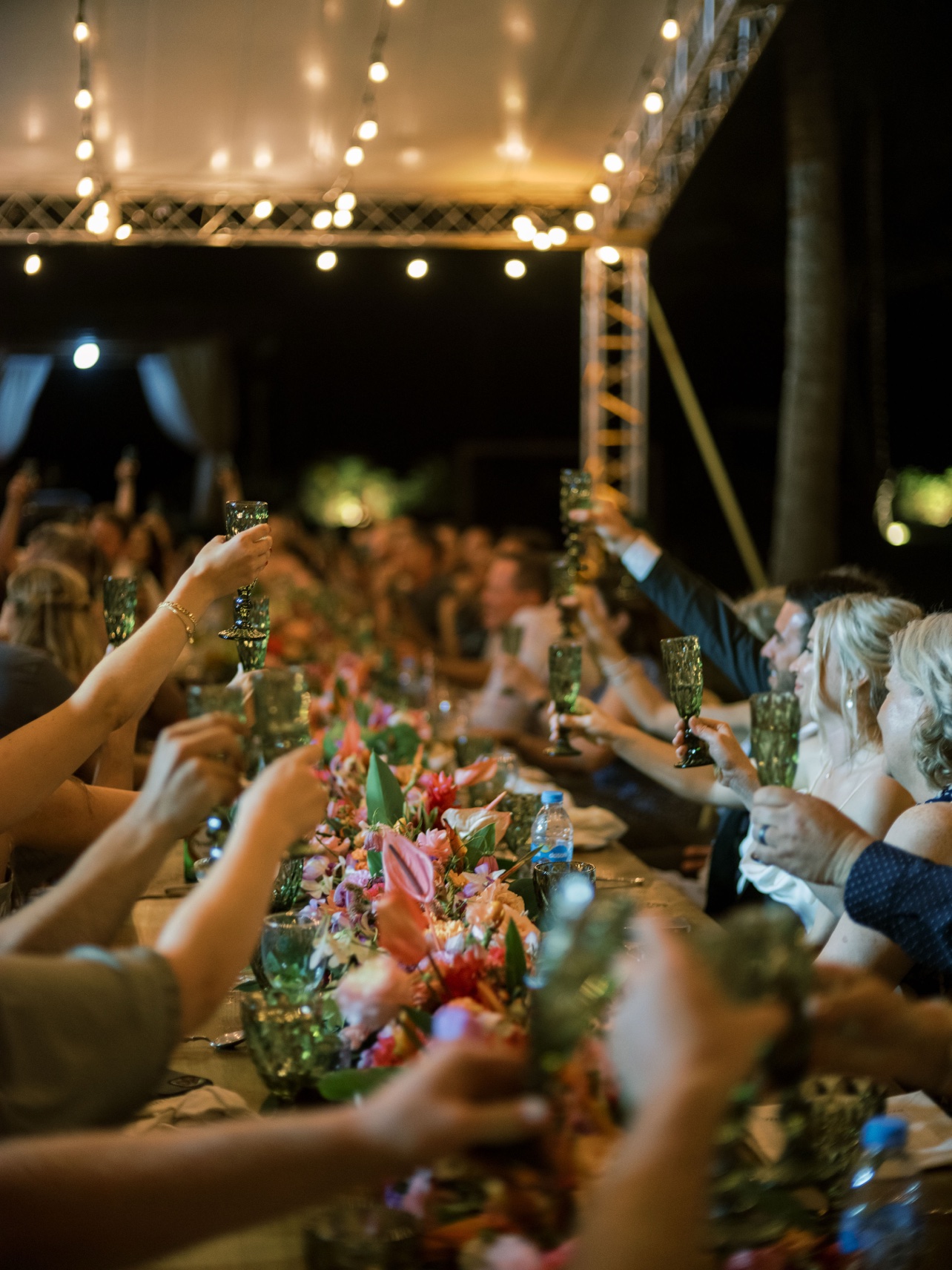 Brindis nocturno bajo la carpa con luces colgantes
