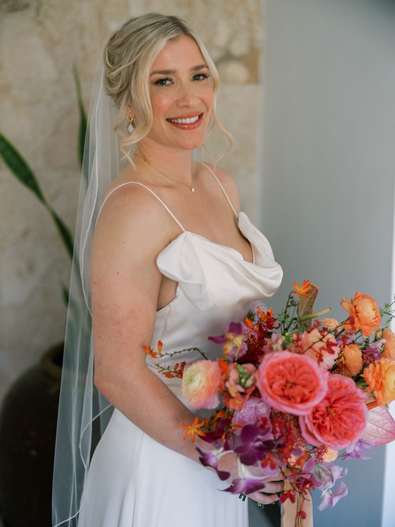 Retrato de la novia con un ramo tropical naranja, rosado y morado