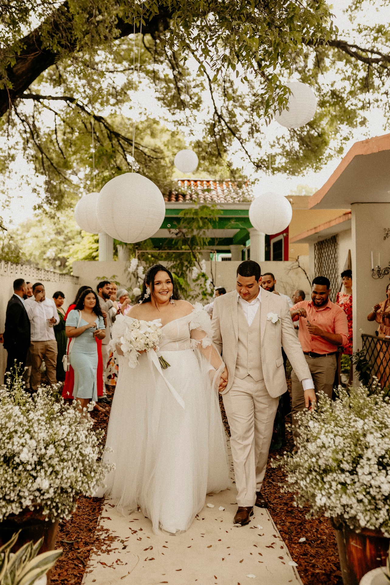 Pareja recién casada caminando entre flores blancas en la ceremonia