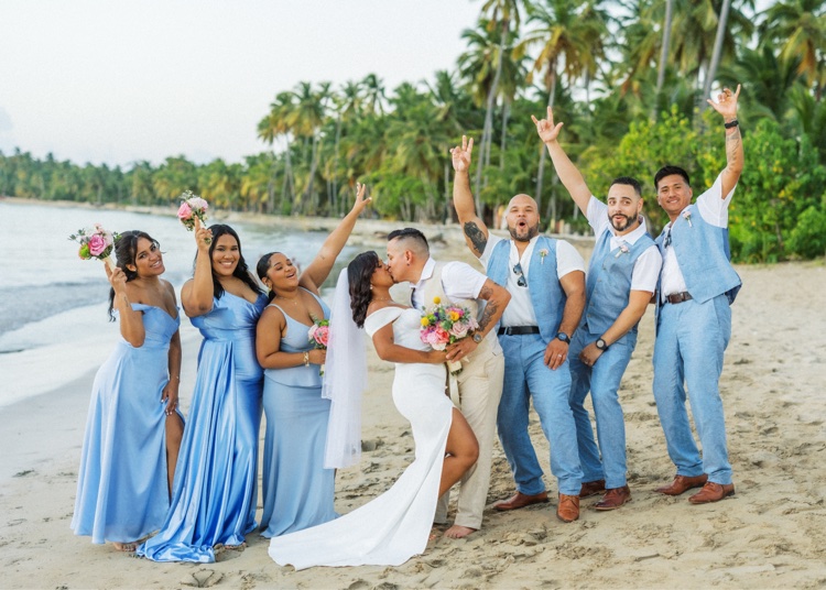 Novios y cortejo celebrando juntos en la playa