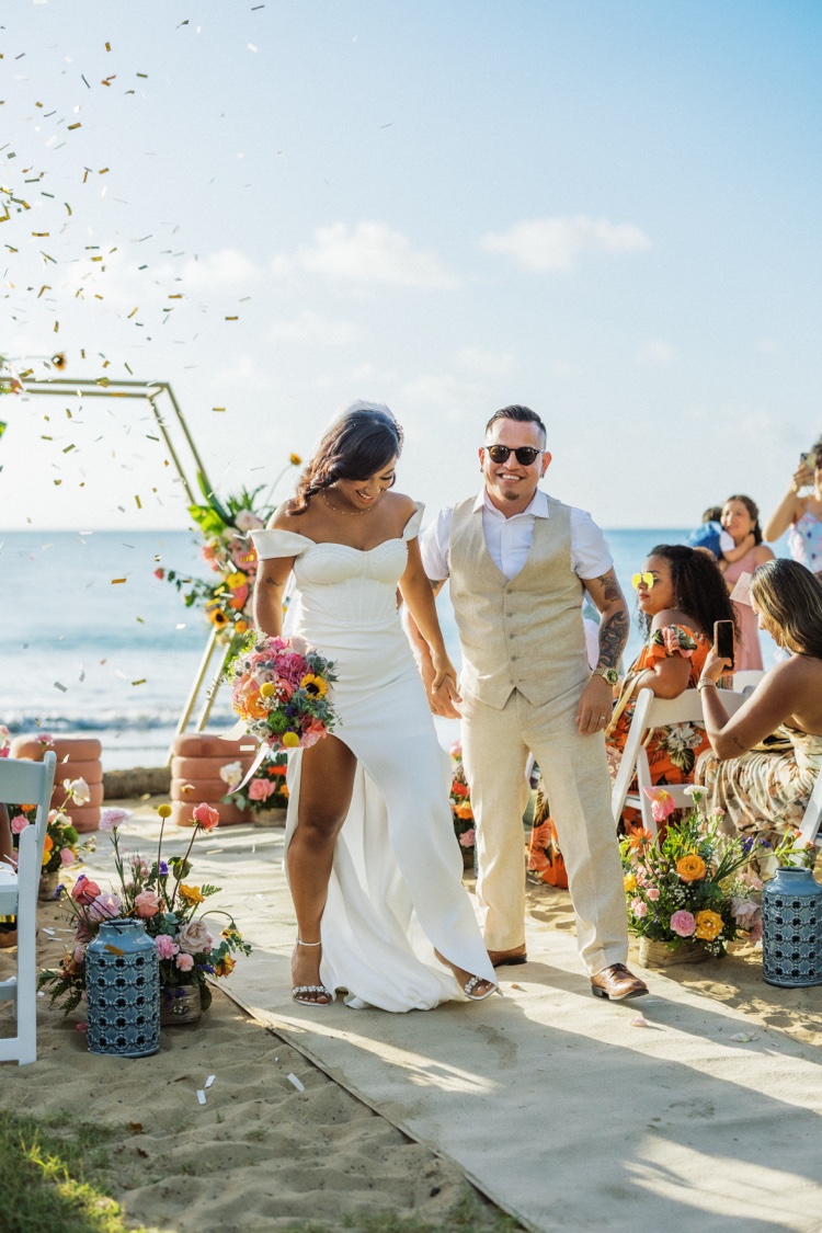 Recién casados caminando entre sus invitados frente al mar