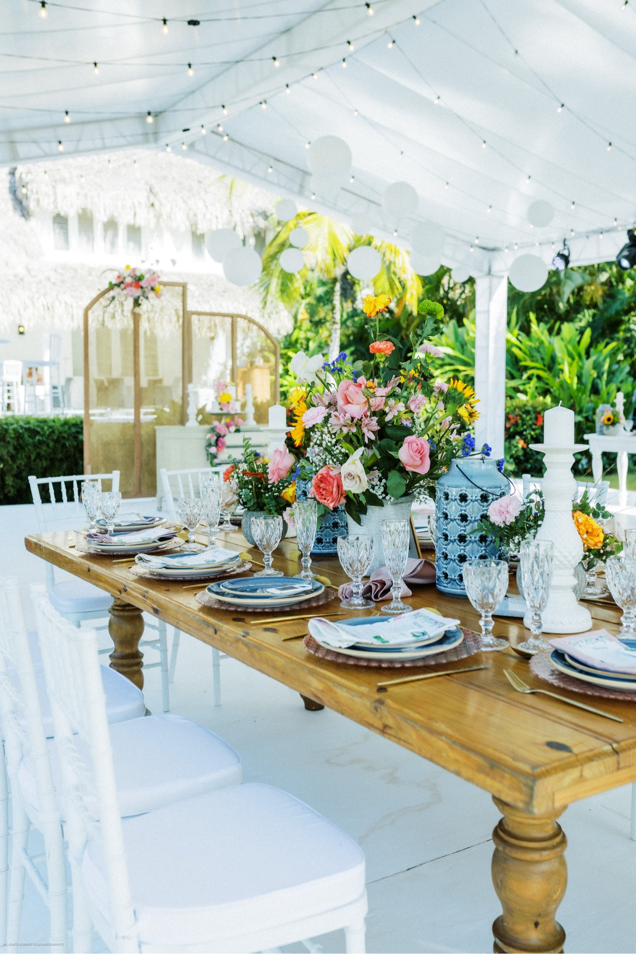Mesa de boda con flores de colores bajo una carpa luminosa