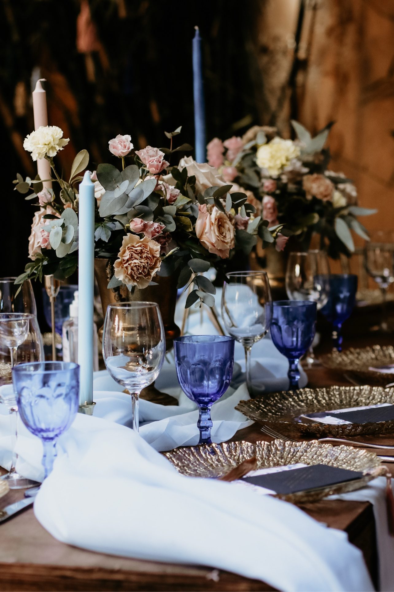 Detalle de mesa con flores, velas y copas azules