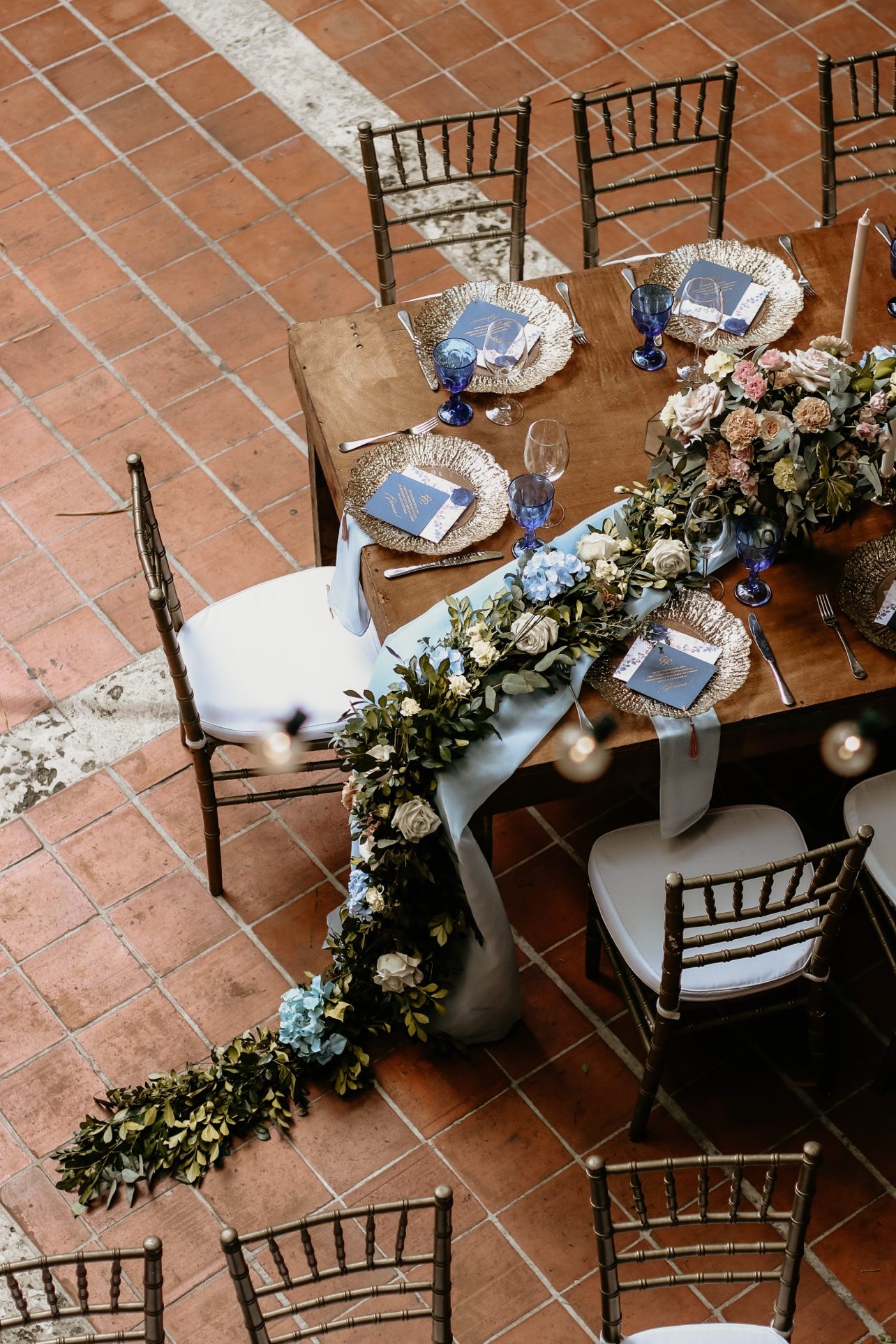 Mesa con camino de guirnalda floral y copas azules