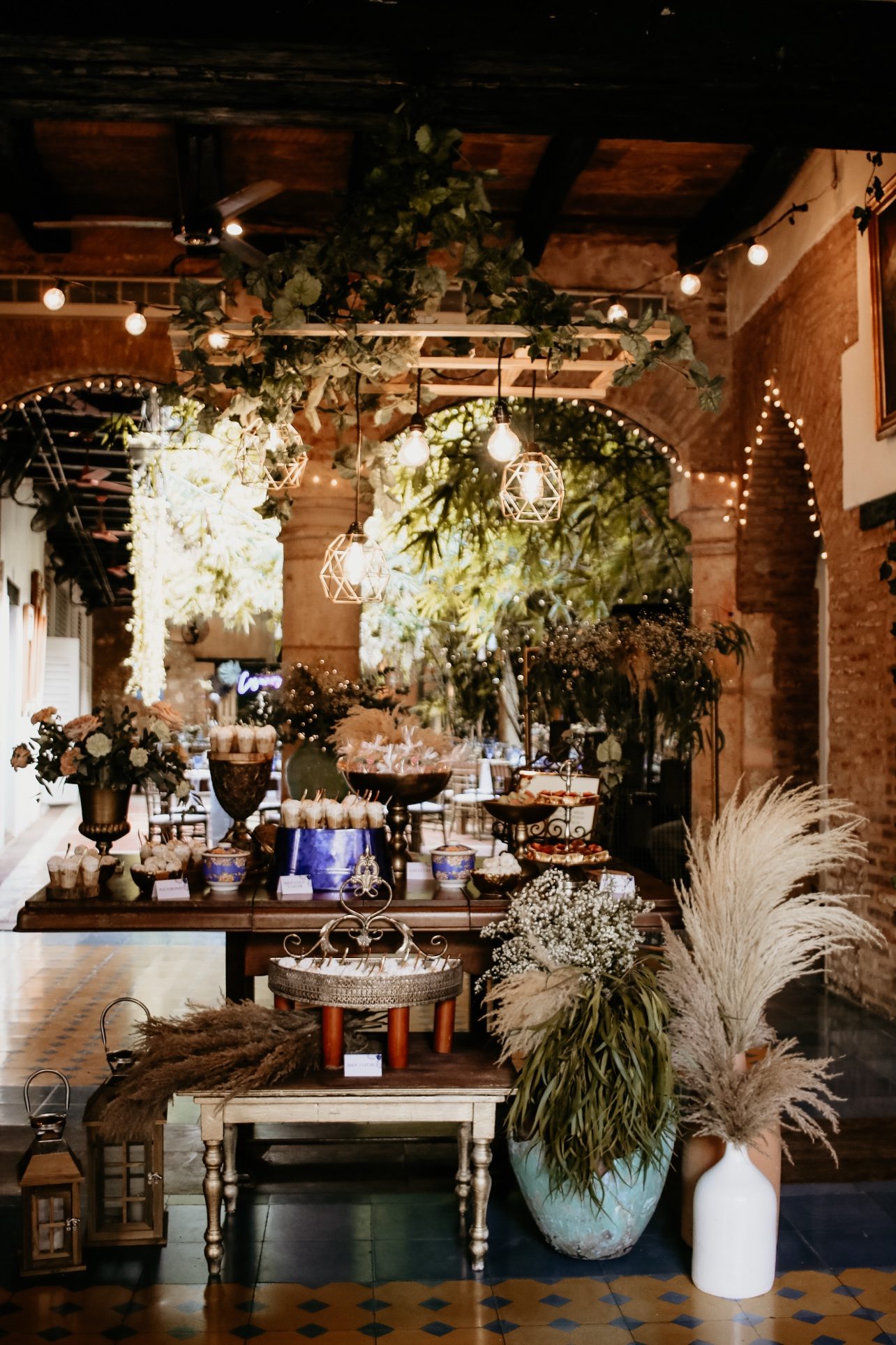 Mesa de postres con decoración de pampas y luces